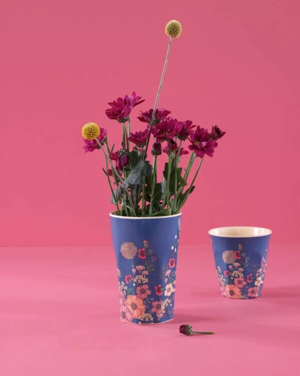 Rice Melamin Becher Größe L mit blauem Flower Collage Print fotografiert vor pinkem Hintergrund mit kleinem Becher des gleichen Designs und einem Strauß pinker Blumen