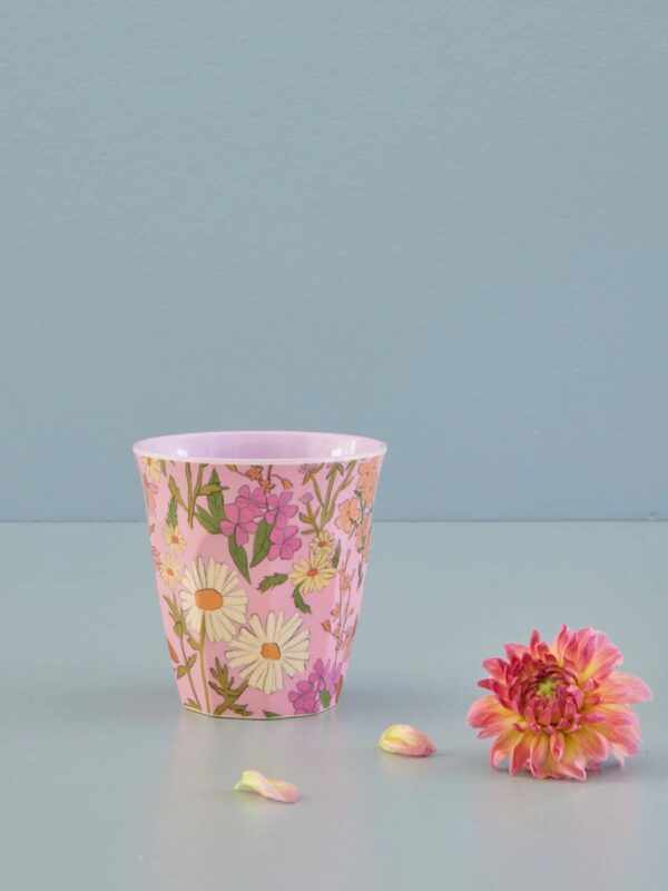 Rice Melamin-Becher Größe M mit Daisy Dearest Print fotografiert vor hellgrauem Hintergrund mit pinkfarbener Blume
