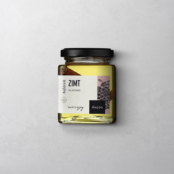 Wajos Honig mit Zimt im eckigen wiederverschließbaren Glas mit schwarzem Deckel und weißem Etikett