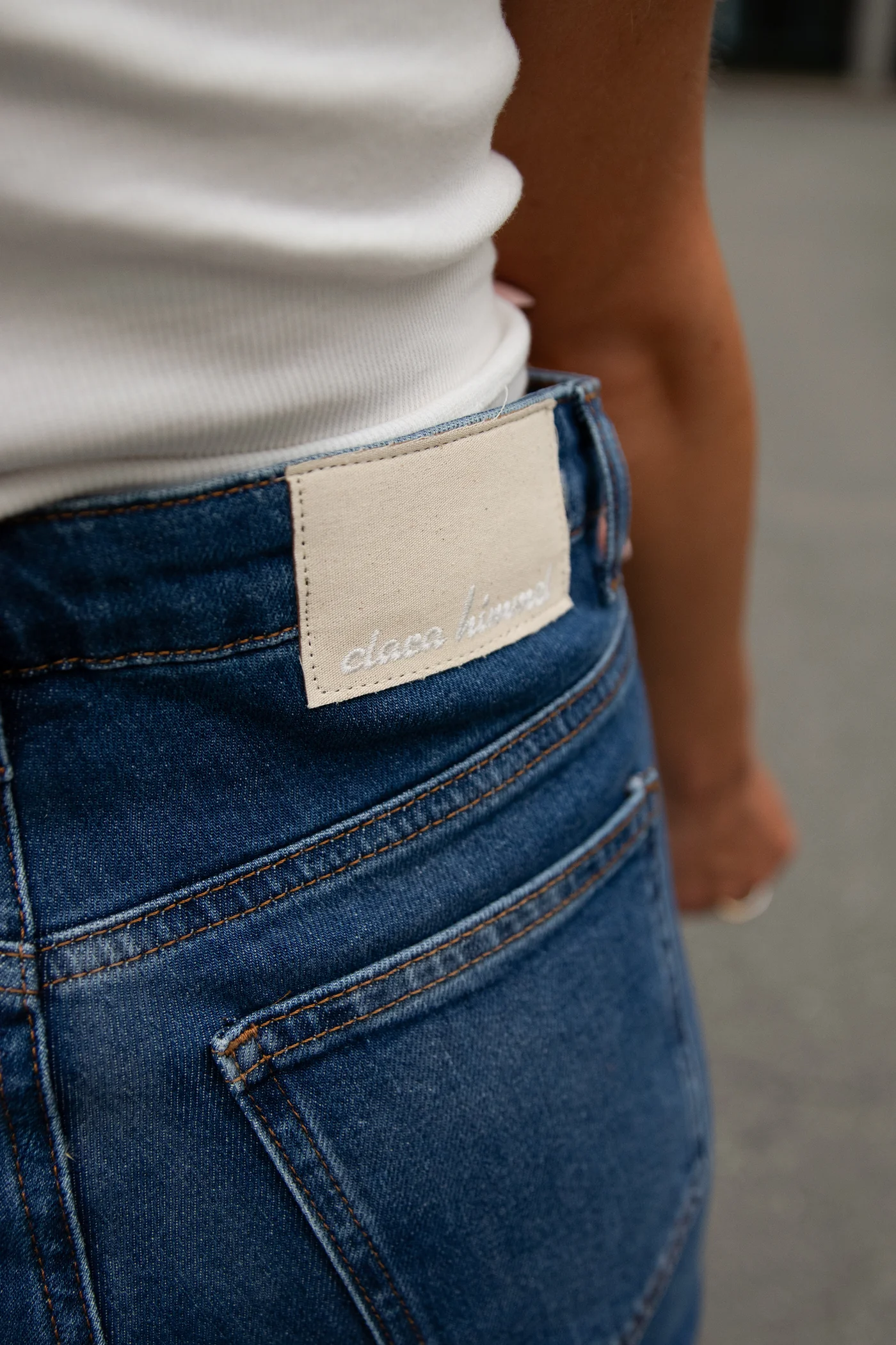 Slim_Fit Jeans in Indigo Blau von Clara Himmel mit ausgefranstem Saum am Bein (Detailansicht Helles Logo am Gürtelbund)
