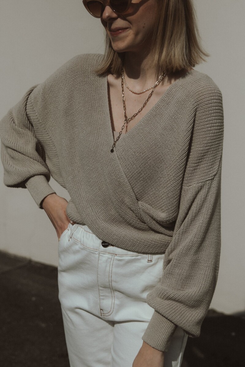 Wrap-Pullover in Beige von Clara Himmel getragen von Frau mit langen braunen Haaren und weißer Mom-Jeans