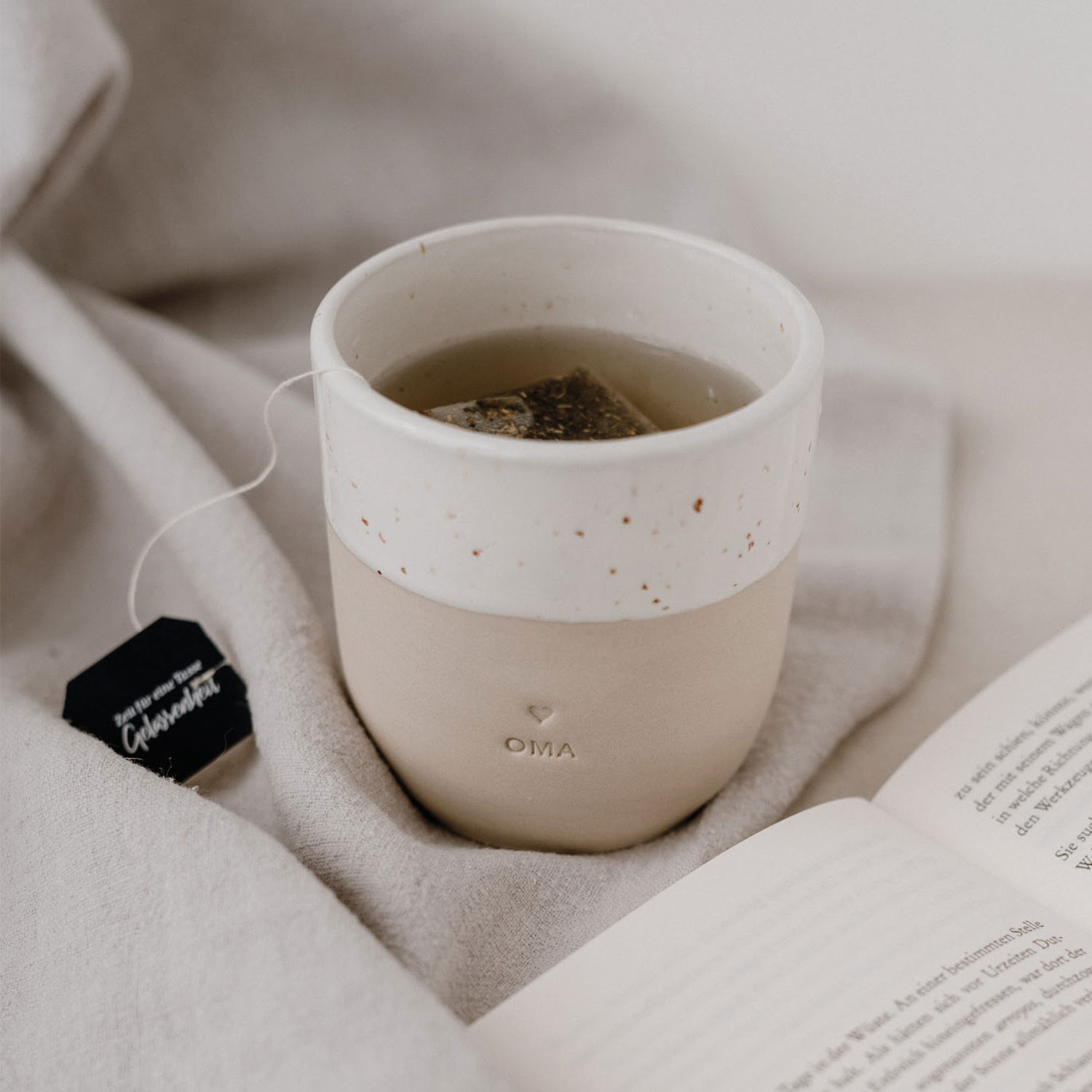 Eulenschnittbecher mit Blinddruck Oma mit Teebeutel in der Tasse neben Buch fotografiert