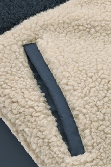 Wendejacke von Liewood in den Farben Blau, Beige, Weiß. Eine Seite in Teddy und eine Seite in Stepp mit Kapuze (Detail-Ansicht Tasche)