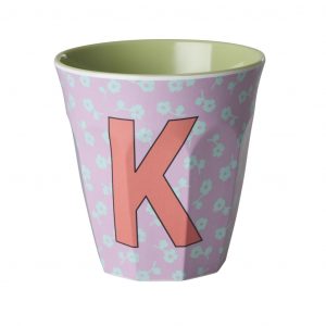 Buchstabenbecher von Rice mit Buchstabe K in Koralle auf fliederfarbigem Hintergrund mit türkisfarbigen Blumen
