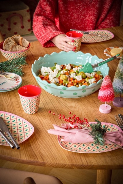 Medium Becher von Rice in Beige mit Allover grünen Tannenbäumen, Rosa Rand und roter Innenfarbe auf Holztisch mit weiteren Artikeln von Rice