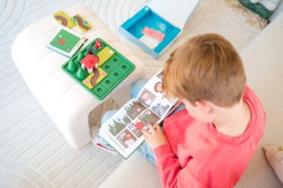 Kind liest das Bilderbuch, das bei dem Smart Games Spiel Rotkäppchen mit dabei ist